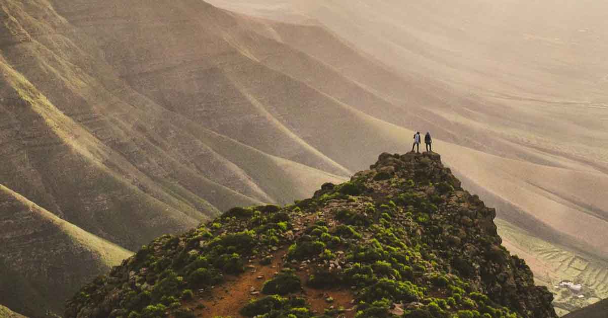Découvrez la beauté tranquille de la nature avec ce paysage pittoresque, mettant en scène des collines verdoyantes, un ciel bleu clair, un cadre montagneux serein et une route sinueuse idéale pour voyager.